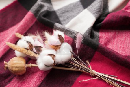 Photo for Bouquet of cotton, fluffy ears of lagurus, poppy. the bouquet lies on a marsala-colored checkered fabric. cozy background. - Royalty Free Image