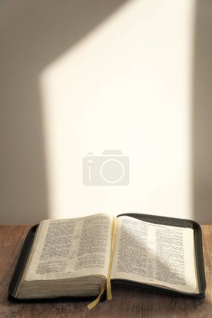Foto de Biblia abierta sobre la mesa. fondo claro, luz solar. Iluminación. fe, religión. - Imagen libre de derechos
