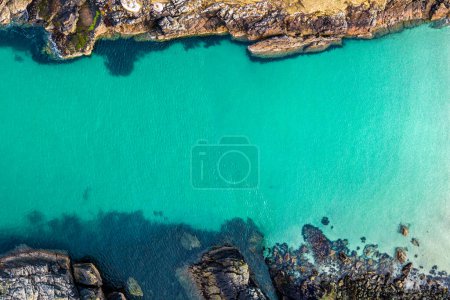 Aerial drone view of Port of Stoth on the Isle of Lewis. Turquoise water surrounded by outcrops and cliffs of surrounding cove in Outer Hebrides