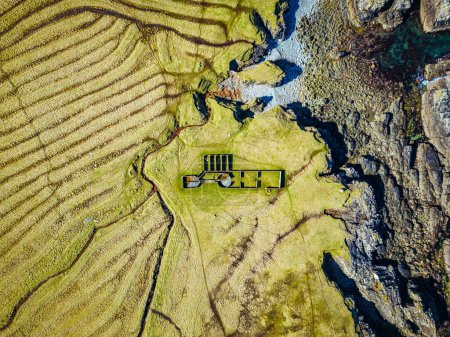 Aerial view of livestock farming pen for shearing sheep on Isle of Lewis, UK. Top-down view of a sheep farm on Scottish coastline with farm building.