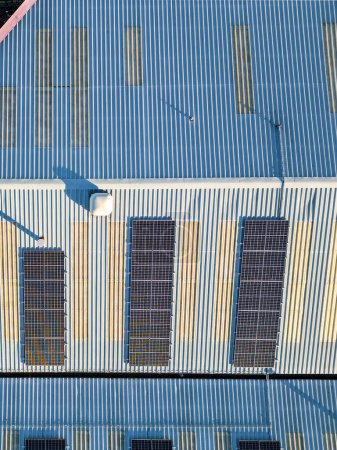 Vertikaler Blick aus der Vogelperspektive auf Solarzellen für die Versorgung mit erneuerbaren Energien auf dem Dach eines Industriegebäudes, Großbritannien. 