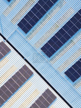 Aerial birds eye vertical view of solar panel photovoltaic cells for renewable energy supply on roof of industrial factory building, UK. 