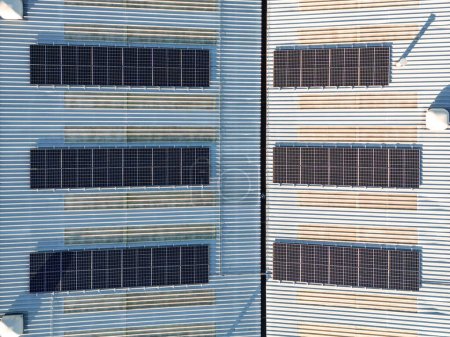 Aerial birds eye view of solar panel photovoltaic cells for renewable energy supply on roof of industrial factory building, Yorkshire, UK. 