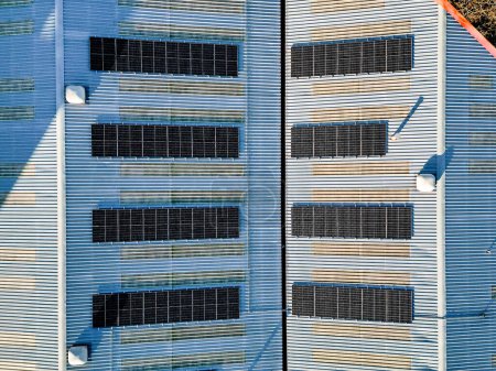 Aerial birds eye view of solar panel photovoltaic cells for renewable energy supply on roof of industrial factory building, Yorkshire, UK. 