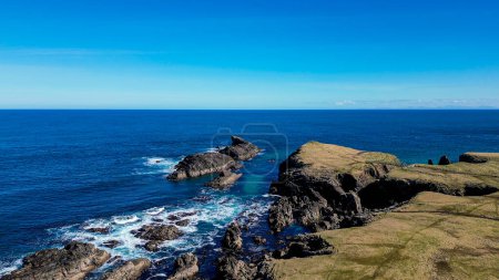 Dun Eistean Iron Age Archaeological Site on Isle of Lewis, Scotland. Rugged Scottish coastal landscape with blue sky.