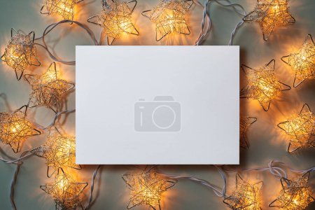 Photo for Christmas winter festive ornament. Blank paper card  and Christmas lights decoration background. Invitation Christmas holiday party. Flat lay, top view, copy space. - Royalty Free Image