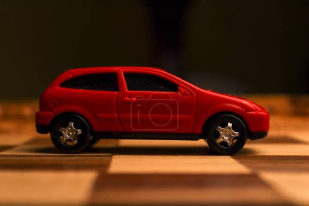 Téléchargez les photos : Jouet de véhicule rouge sur un échiquier avec divers motifs uniques dessinés dessus - en image libre de droit