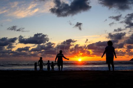 Foto de A Mom feeling cut off from her family at the beach during sunset - Imagen libre de derechos