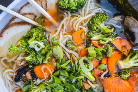 Photo for A bowl of ramen with chopsticks and broccoli on top - Royalty Free Image