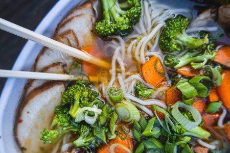 Photo for A bowl of ramen with chopsticks and broccoli on top - Royalty Free Image