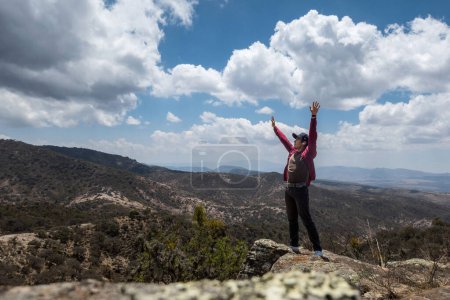 Photo for A man stands on top of a mountain with his arms raised in semi desert. - Royalty Free Image