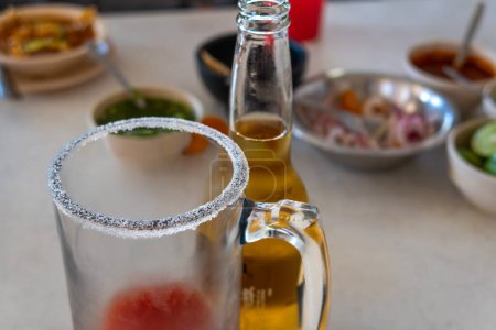 Una bebida mexicana Michelada de cerveza, jugo de tomate, limón y sal. Con espacio para texto.