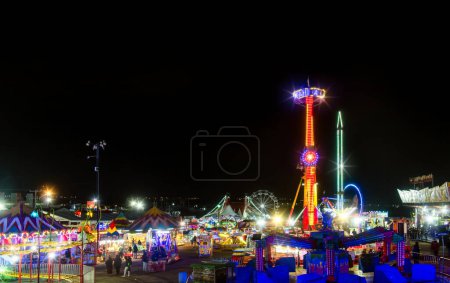 A Mexican fair with rides and lights at night, with space for text