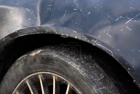 A Scratches on car fender and worn tire, with space for text