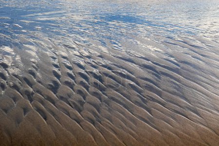 A Background of waves in the sand generated by sea waves and sun shine