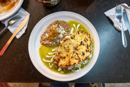 Foto de Una comida casera Chilaquiles mexicanos con salsa verde, pollo, tototopos y frijoles - Imagen libre de derechos