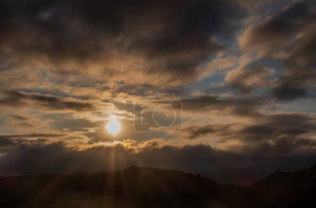 Ein Sonnenuntergang mit Sonnenstrahlen zwischen den Wolken, mystische Szene mit Platz für Text