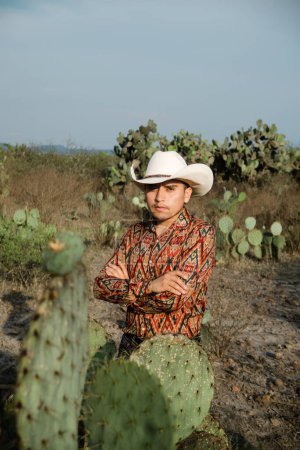 A young man with mexican hat in a desert landscape with cactus