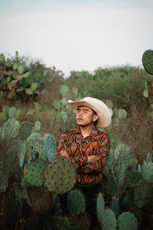 A mexican man with sombrero in a cactus landscape