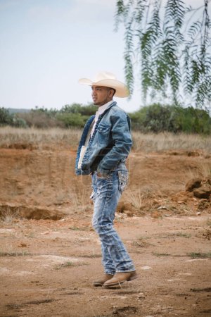 Ein Cowboy in Jeans und Hut steht unter dem Himmel mit flauschigen Wolken und arbeitet auf einem Bauernhof