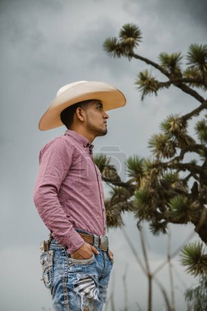 Ein Cowboy mit Bart, Jeans, kariertem Hemd und Cowboyhut genießt die Natur unter freiem Himmel