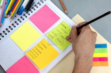 Etudiant écrit des notes dans un carnet et des messages colorés