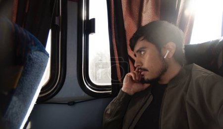 Un joven reflexivo viajando y sentado en un autobús económico, con espacio para el texto