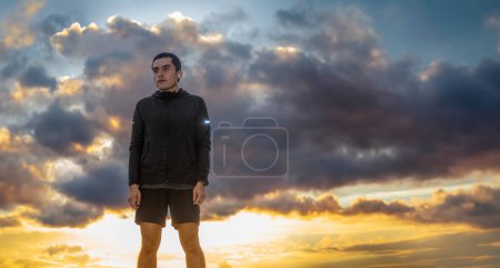 A Serious man wearing sportswear, sky in the background representing effort, with space for text