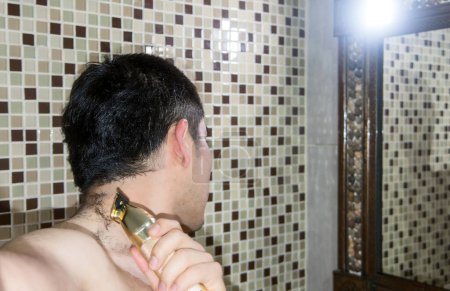 A Man cutting his own hair with a clipper, with space for text