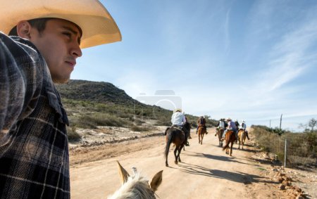 Un homme faisant une promenade avec des amis à cheval dans un chapeau à travers une campagne semi-déserte, avec de l'espace pour le texte
