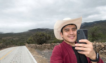 Un hombre en sombrero haciendo videollamadas con su teléfono en la zona con mala señal, con espacio para el texto