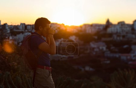 Un jeune homme prend une photo avec son appareil photo au coucher du soleil