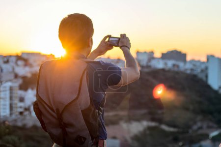 Un jeune homme prend une photo avec son appareil photo au coucher du soleil, avec de l'espace pour le texte