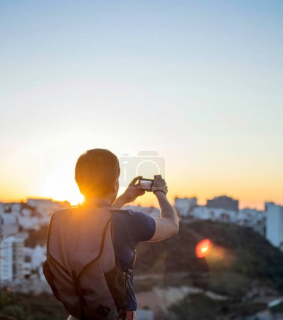 Ein junger Mann beim Fotografieren mit seiner Kamera bei Sonnenuntergang