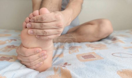 Eine Person massiert ihren Fuß wegen Schmerzen in der Sohle, im Fußgewölbe und in den Zehen. Platz für Text rechts.