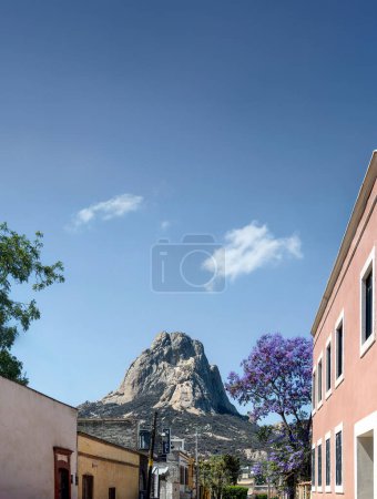 A Bernal Peak, Monolith in Queretaro, Mexiko, mexikanische Stadt mit alten Häusern und Jacaranda-Blumen, mit Platz für Text oben.