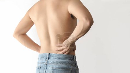 Ein Mann ohne Hemd, der unter Taille und Rückenschmerzen leidet, mit weißem Hintergrund und Platz für Text