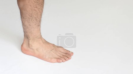 Foto de Un pie adulto en primer plano sobre un fondo blanco con espacio para el texto, mostrando la vista interior del tobillo. - Imagen libre de derechos