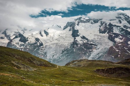 Photo for Path among snow mountains. Zermatt, Swiss Alps. Adventure, hiking in Switzerland, Europe. Place for loneliness, silence and relax. Green grass and stones. - Royalty Free Image