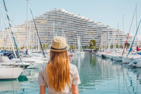 Photo for Blonde hair woman in a hat standing with her back on sea, yachts and boats background. Vacation in Europe. Nice, French riviera. Travel photo. - Royalty Free Image