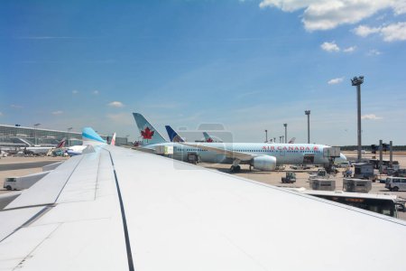 Téléchargez les photos : Aéroport de Francfort Allemagne 02 août 2022 - Vue de la fenêtre de l'aéronef sur une aile et une vue de l'aérogare et d'une machine d'Air Canada en cours de chargement - en image libre de droit