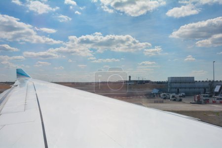 Téléchargez les photos : Aéroport de Francfort Allemagne 02 août 2022 - Vue par la fenêtre sur une aile d'avion avec vue sur l'aéroport avec ciel bleu - en image libre de droit