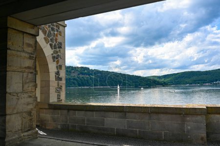 Photo for View of the Edersee lake with part of the dam wall, with sailing boat, blue sky and clouds, in Hesse, Germany - Royalty Free Image