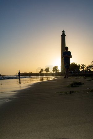 Photo for Lighthouse in Maspalomas ( Faro de Maspalomas ) on the Canary Island of Gran Canaria in Spain at sunset with people, sandy beach and sea - Royalty Free Image