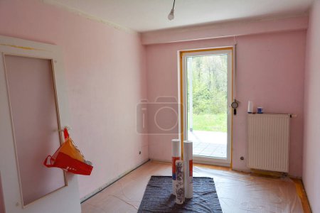 Foto de Paredes rosadas con techo de un apartamento durante la renovación, la puerta suspendida se encuentra en la pared, con una ventana en la habitación - Imagen libre de derechos