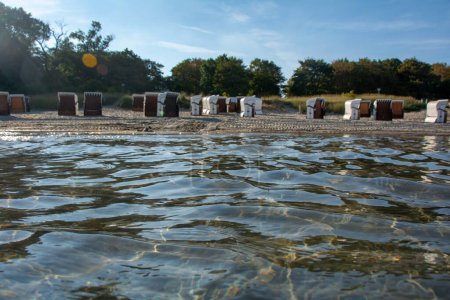 Blick auf verschwommene Liegestühle am Sandstrand vom Wasser der Ostsee auf Poel, Deutschland
