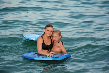 Zwei Kinder mit Schwimmbrett im Wasser