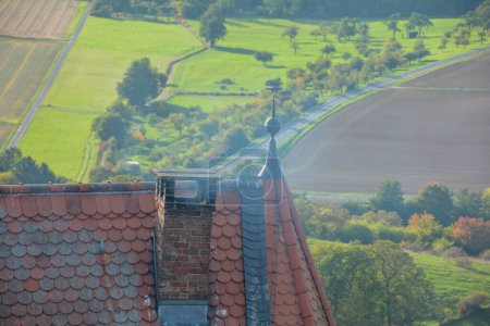 Rauchender Schornstein auf dem Dach eines alten Schlosses mit Blick auf eine grüne Landschaft von oben