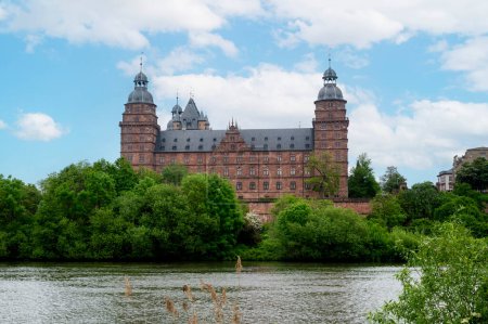 View of Johannisburg Castle in Aschaffenburg with a river and a blue sky