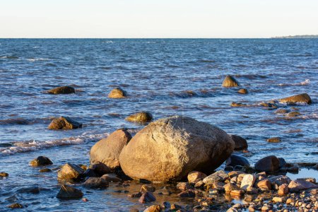 Photo for Big stones lie in the water on the Baltic Sea coast, with waves and horizon - Royalty Free Image